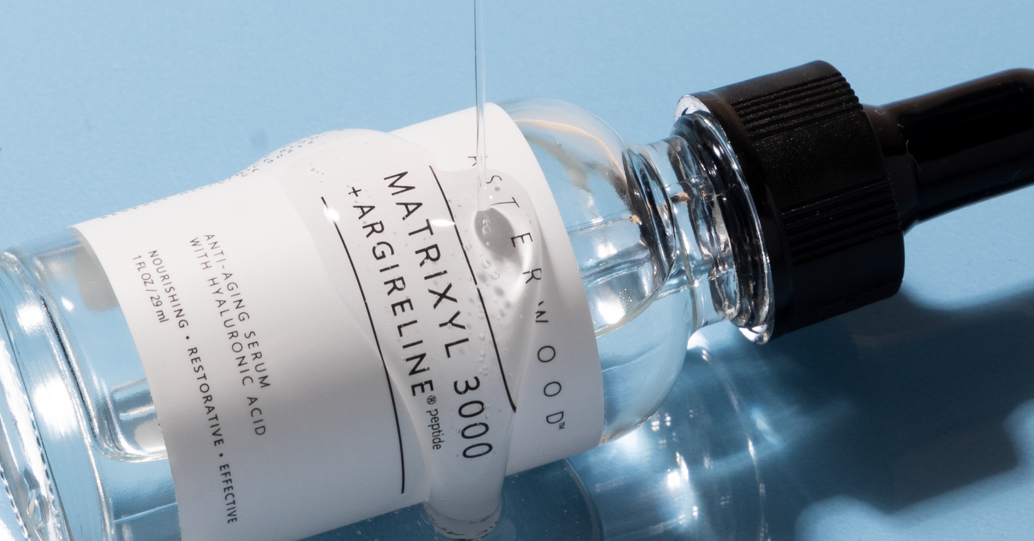 Asterwood Matrixyl 3000 and Argireline serum bottle resting at an angle on a blue background, label visible.