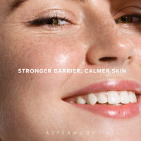 Close-up of a freckled face with glowing skin and the line 'stronger barrier, calmer skin' to illustrate cleanser benefits.