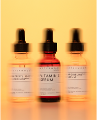 The Fine Line Trio backlit on a warm yellow background: Matrixyl 3000 + Argireline, Vitamin C, and Argireline serum dropper bottles.