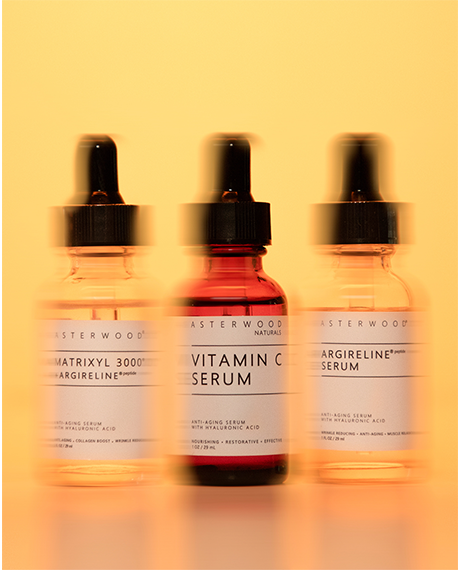 The Fine Line Trio backlit on a warm yellow background: Matrixyl 3000 + Argireline, Vitamin C, and Argireline serum dropper bottles.