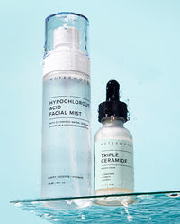 Asterwood Hypochlorous Acid Facial Mist and Triple Ceramide Barrier Serum sitting on a glass surface with water splashing, set against an aqua background.