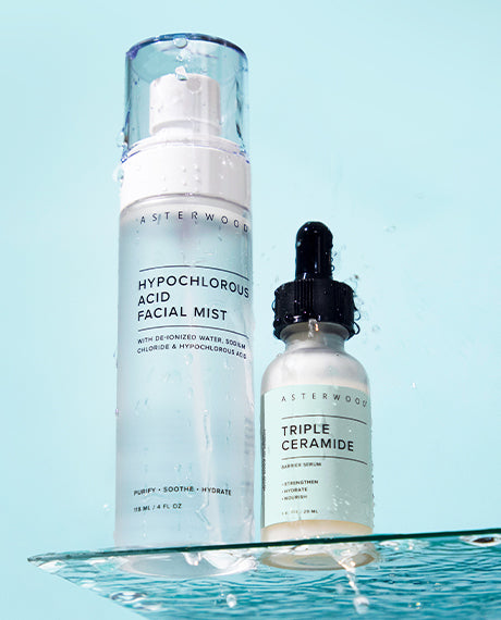 Asterwood Hypochlorous Acid Facial Mist and Triple Ceramide Barrier Serum sitting on a glass surface with water splashing, set against an aqua background.