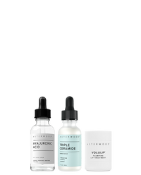 Asterwood Winter Glow Bundle on white: the clear Hyaluronic Acid Serum, the light blue Triple Ceramide Barrier Serum, and the white Volulip Plumping Lip Treatment tube.